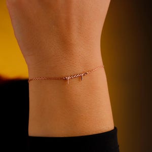 May include: A delicate rose gold bracelet with the name "spennyer" in a cursive font. The bracelet is worn on a wrist, and the chain is thin and elegant. The overall aesthetic is minimalist and stylish, suitable for everyday wear.
