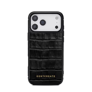 A crocodile-textured iPhone case. The case features a Glossy, reptile-inspired Glossy with raised scales that give it a luxurious, high-end look. The phone case has a black border, highlighting its sleek and modern design. The person's hand, with neatly manicured red nails, is seen against a backdrop of denim jeans, adding a stylish, fashionable touch to the image. The brand name "GENTCREATE" is subtly visible on the case.