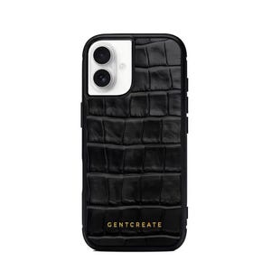 A crocodile-textured iPhone case. The case features a Glossy, reptile-inspired Glossy with raised scales that give it a luxurious, high-end look. The phone case has a black border, highlighting its sleek and modern design. The person's hand, with neatly manicured red nails, is seen against a backdrop of denim jeans, adding a stylish, fashionable touch to the image. The brand name "GENTCREATE" is subtly visible on the case.