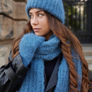 Puede incluir: Un gorro de punto azul difuso, una bufanda de punto azul a juego y un par de manoplas de punto azul. El conjunto presenta una construcci&oacute;n de hilo grueso y texturizado en un color azul polvo s&oacute;lido, ofreciendo un aspecto coherente.