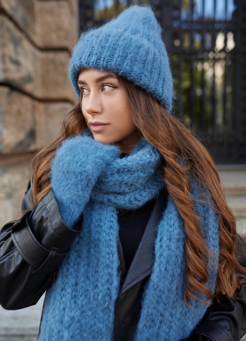 Puede incluir: Un gorro de punto azul difuso, una bufanda de punto azul a juego y un par de manoplas de punto azul. El conjunto presenta una construcci&oacute;n de hilo grueso y texturizado en un color azul polvo s&oacute;lido, ofreciendo un aspecto coherente.