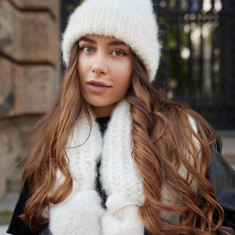 Puede incluir: Un gorro de punto blanco, una bufanda de punto blanca a juego y manoplas de punto blancas. Los accesorios presentan una textura suave y difusa con un patr&oacute;n de punto acanalado. Estos art&iacute;culos de invierno se usan juntos.