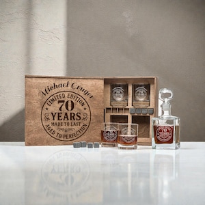 Puede incluir: Un juego de caja de madera con una jarra, cuatro vasos y piedras de whisky. El juego está grabado con "Michael Cruger Limited Edition 70 Years Aged to Perfection Made to Last". Los vasos y la jarra tienen el logotipo "70 Years".