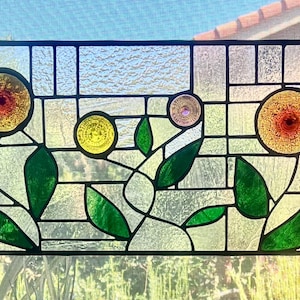 Puede incluir: Panel de vidrieras con flores amarillas y rojas estilizadas con hojas y tallos verdes. El panel es rectangular con un borde negro y un fondo en forma de rejilla. Las flores tienen un aspecto texturizado.