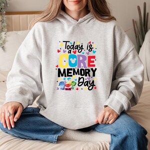 May include: Gray hoodie with a graphic print of the characters from the movie Inside Out. The text on the hoodie reads "Today is a CORE MEMORY Day".