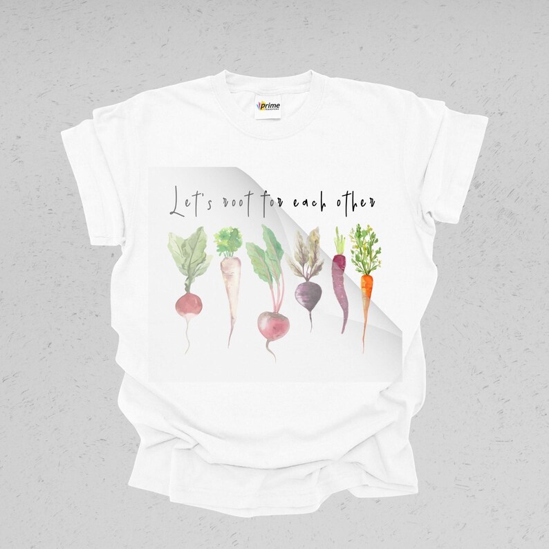 K&ouml;nnte beinhalten: Wei&szlig;es T-Shirt mit einer Aquarell-Illustration von Gem&uuml;se und dem Text "Let's root for each other".