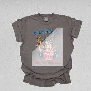 May include: Dark gray t-shirt with a graphic featuring a woman dressed as the Statue of Liberty holding a hot dog. Text reads "YOU LOOK LIKE THE 4TH OF JULY" and "MAKES ME WANT A HOT DOG REAL BAD."