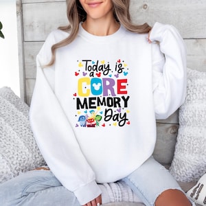 May include: White sweatshirt with a colorful graphic that says "Today is a CORE MEMORY Day" with a Mickey Mouse head inside the word "CORE" and characters from the movie Inside Out.