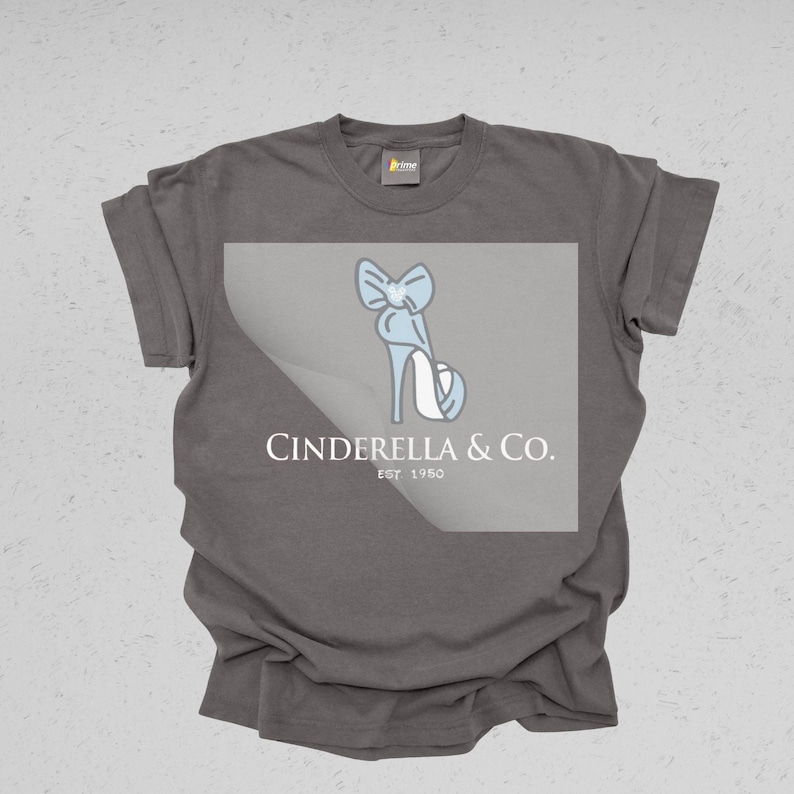 May include: A gray t-shirt featuring a light blue illustration of a high-heeled shoe with a bow. The text "Cinderella & Co. EST 1950" is printed below the shoe design in white.