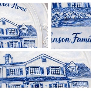 May include: A white decorative plate with a blue illustration of a house. The plate has the words "sweet Home" and "Johnson Family" written on it. The house illustration includes windows, a garage, and a chimney.
