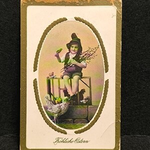 May include: Vintage Easter postcard featuring a child in a green hat holding a bird and pussy willow branches. The child is seated on a small wooden structure with a chicken and other decorations. The text "Fröhliche Ostern" is at the bottom.