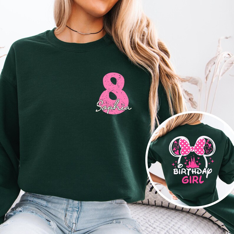 A woman wearing a green sweatshirt with a pink number 8 and a pink Minnie Mouse design, along with the text "Sophia 8" and "Birthday Girl" printed on it.