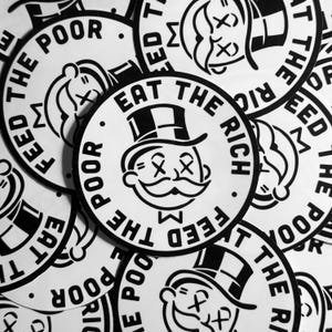May include: A black and white sticker with the text "Eat the Rich" and a Monopoly Man character with an X over his eyes. The sticker is surrounded by other stickers with similar designs.