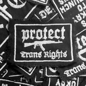 May include: Black and white embroidered patch with the text "protect arms rights" and a stylized image of a rifle.