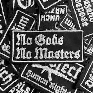 May include: A black and white embroidered patch with the text "No Gods No Masters" in a gothic font.