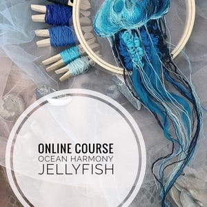 Könnte beinhalten: Online-Kurs mit dem Titel "Ozeanharmonie Qualle" mit einer blauen und weißen gestickten Qualle in einem hölzernen Stickrahmen.