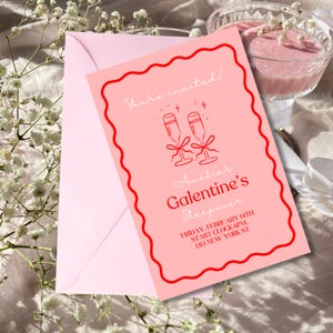 May include: Pink invitation card with a red border and white text. The card says "You're invited!" and features two champagne glasses with a red bow. The text also says "Amelia's Galentine's Sleepover" and includes the date, time, and address.