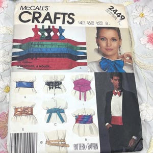 May include: A vintage McCall's Crafts pattern envelope featuring illustrations of various tie and belt designs. The cover includes images of a woman and a man wearing the accessories, with the text "McCall's Crafts" prominently displayed.