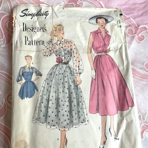 May include: Vintage Simplicity Designer's Pattern featuring illustrations of dresses. The pattern includes a dress with a polka dot skirt and sheer sleeves, and a pink dress with a collared neckline. The pattern is size 16.