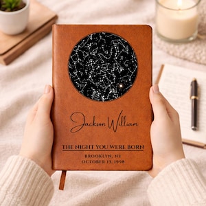 May include: A brown leather journal featuring a black and white star map within a circle. The journal is inscribed with the name "Jackson William", the text "THE NIGHT YOU WERE BORN", and the location and date.