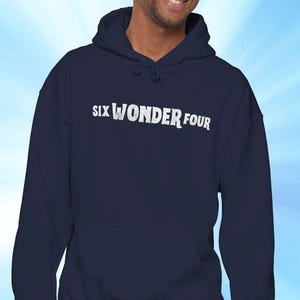 Op de afbeelding: Marineblauwe hoodie met de witte tekst "SIX WONDER FOUR". De afbeelding toont een persoon die de hoodie met trekkoord draagt.