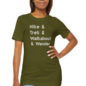 K&ouml;nnte beinhalten: Olivgr&uuml;nes T-Shirt mit den wei&szlig;en Worten "Hike & Trek & Walkabout & Wander". Das Shirt hat einen Rundhalsausschnitt und besteht aus einem weichen Material.