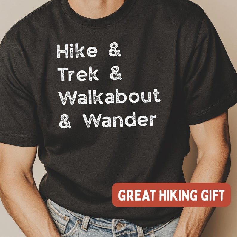 K&ouml;nnte beinhalten: Schwarzes T-Shirt mit wei&szlig;em Text: "Hike & Trek & Walkabout & Wander." Ein rotes Rechteck unten zeigt "GREAT HIKING GIFT." Das Shirt ist ein l&auml;ssiger Stil, geeignet f&uuml;r Wanderfreunde.