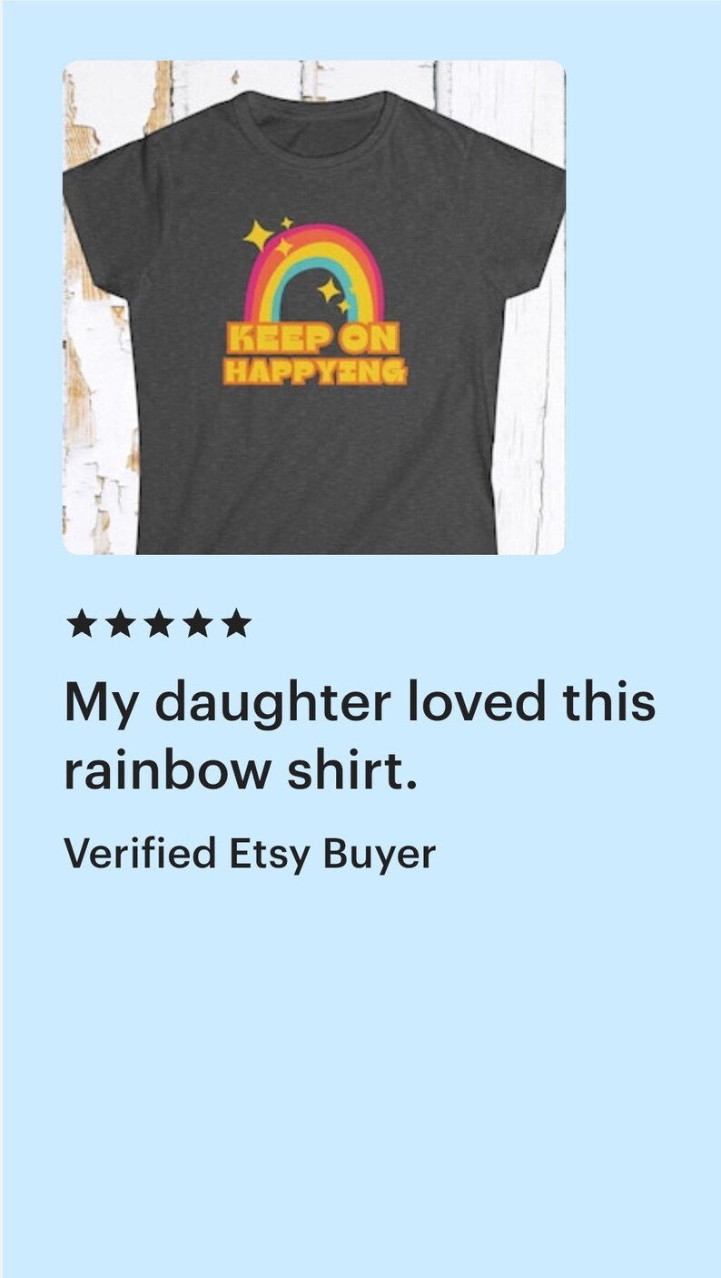Op de afbeelding: Donkergrijs t-shirt met een kleurrijke regenboogafbeelding en de tekst "KEEP ON HAPPYING". Het regenboogontwerp bevat rode, oranje, gele, groene en blauwe bogen, met gele sterren erboven. Een casual t-shirt.