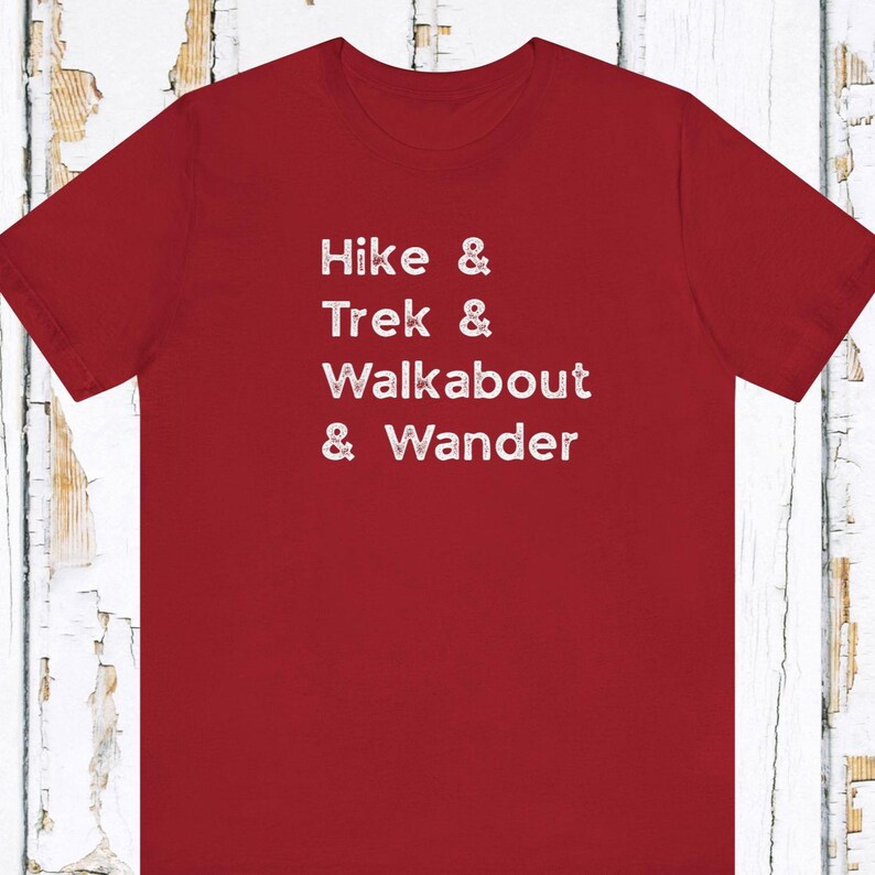 K&ouml;nnte beinhalten: Ein rotes T-Shirt mit dem wei&szlig;en Aufdruck "Hike & Trek & Walkabout & Wander". Das Shirt besteht aus einem weichen Material und eignet sich f&uuml;r Outdoor-Aktivit&auml;ten. Der Text ist mittig auf der Vorderseite platziert.