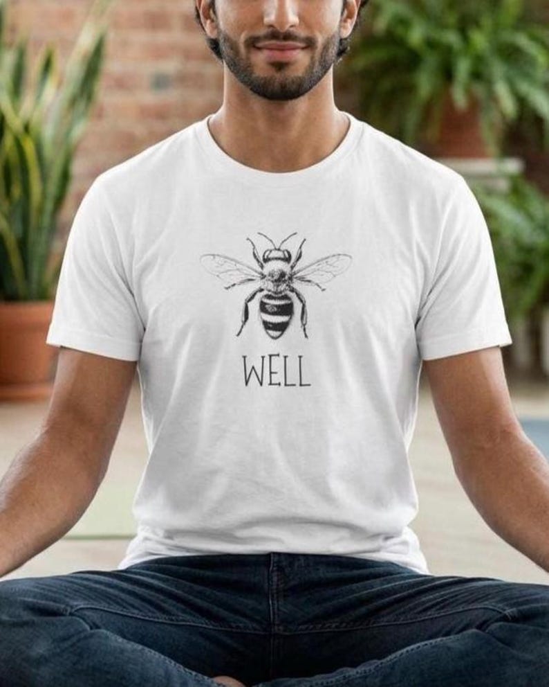 Op de afbeelding: Wit t-shirt met een zwart-witte bijenillustratie en het woord 'WELL' eronder. Het t-shirt is gemaakt van een zacht materiaal en is geschikt voor dagelijks gebruik. Het ontwerp is eenvoudig en opvallend.