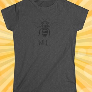 Op de afbeelding: Donkergrijs t-shirt met een gedetailleerde zwarte illustratie van een bij. Onder de bij staat het woord "WELL". Het t-shirt heeft korte mouwen en een ronde hals.