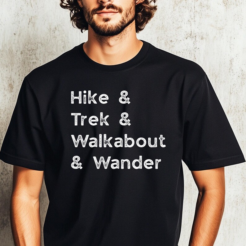 K&ouml;nnte beinhalten: Schwarzes T-Shirt mit wei&szlig;em Text: "Hike & Trek & Walkabout & Wander". Das Rundhals-T-Shirt ist aus weichem Material. Der Text ist mittig auf der Vorderseite. Ein l&auml;ssiges Oberteil f&uuml;r Outdoor-Enthusiasten.