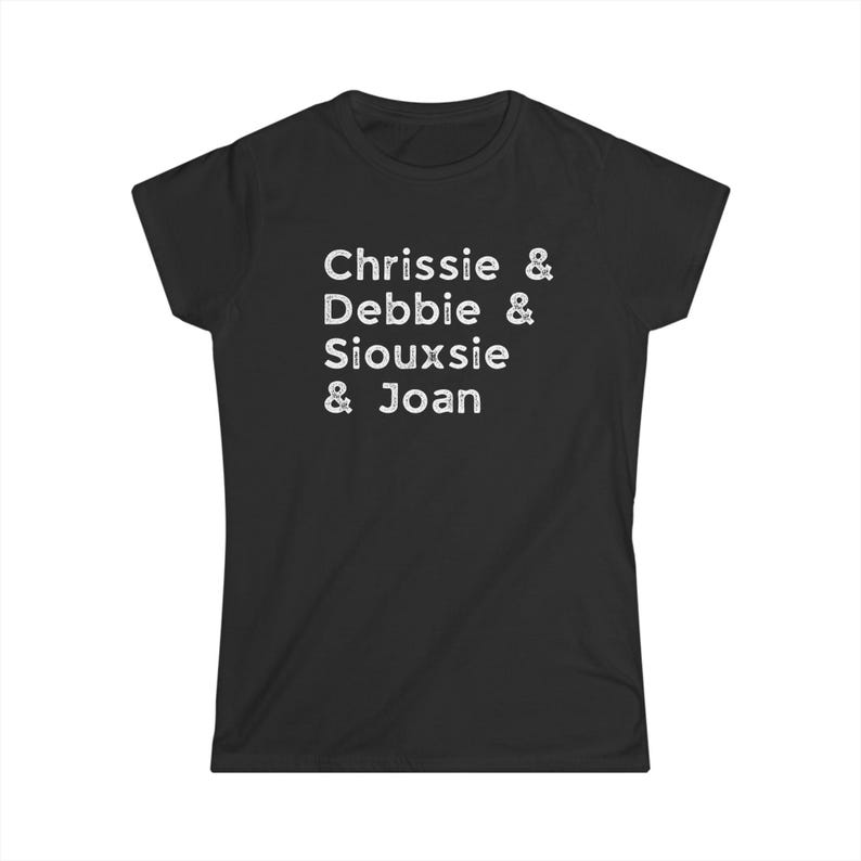 Op de afbeelding: Zwart T-shirt met witte tekst. De tekst luidt "Chrissie & Debbie & Siouxsie & Joan" in een informele, handgeschreven stijl. Het shirt heeft een ronde hals en korte mouwen.
