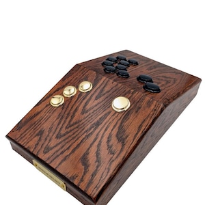 May include: A wooden controller with black and gold buttons. The controller has a dark wood grain finish and a brass plate with the text "SIMMOPSIRELACT" on the bottom.