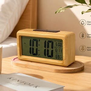 May include: A rectangular digital alarm clock with a natural bamboo finish. The screen displays the time 10:10, the date 6/11, and a temperature of 69 degrees. Features include a silent alarm, temperature display, and a bamboo exterior.