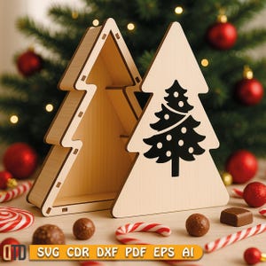 Op de afbeelding: Twee houten kerstboomvormige dozen, waarvan één open, met een zwart boomontwerp op de voorkant. Rode ornamenten en zuurstokken zijn rond de dozen verspreid. De dozen zijn gemaakt van lichtgekleurd hout. De tekst "SVG CDR DXF PDF EPS AI" staat onderaan.