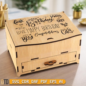 May include: A light-colored wooden box with a drawer and a curved top. The top is decorated with black text that includes "Happy Birthday," "It's a Boy," and "It's a Girl." The box has a small, decorative handle on the drawer.