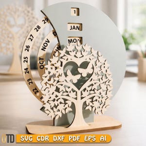 Può includere: Calendario perpetuo in legno con design ad albero, ritaglio a forma di cuore e dettagli a farfalla. Il calendario mostra data, mese e giorno, con un anello rotante per i giorni. La base è rettangolare. Altezza circa 15 cm.