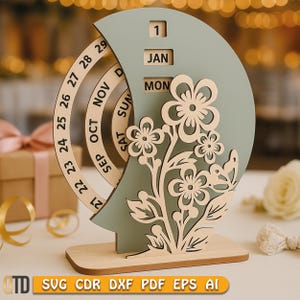 May include: A wooden perpetual calendar with a sage green crescent moon shape and a floral design. The calendar displays the date, month, and day. The base is made of light wood. The image also includes the text "SVG CDR DXF PDF EPS AI".