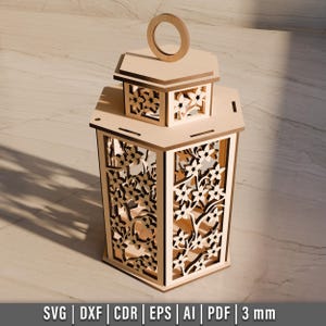 May include: A light-colored wooden lantern with intricate floral cutouts. The lantern has a rectangular base and a smaller, square top with a handle. The design includes the text "SVG | DXF | CDR | EPS | AI | PDF | 3 mm".