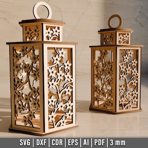 May include: Two wooden lanterns with floral cutouts. The lanterns are rectangular with a square top and a handle. The floral design is cut out of the wood, creating a decorative pattern. The lanterns are made of light-colored wood.