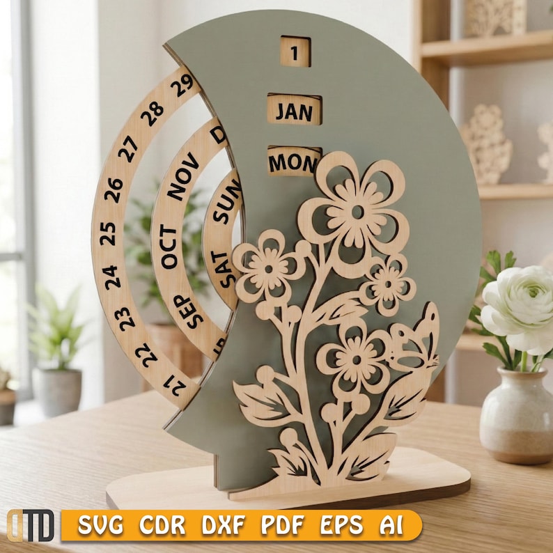 May include: A wooden perpetual calendar with a sage green crescent moon shape and a floral design. The calendar displays the month, day, and date. The base is made of light-colored wood. The text "SVG CDR DXF PDF EPS AI" is at the bottom.