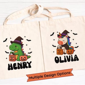 Puede incluir: Dos bolsas de mano beige de Halloween. Una presenta un dinosaurio verde con un sombrero de bruja, sosteniendo una bolsa de "Trick or Treat", con el nombre "HENRY". La otra muestra un unicornio con un sombrero de bruja, con el nombre "OLIVIA". Ambas tienen murciélagos y calabazas.