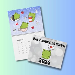May include: Two calendars with frog illustrations. One shows a January calendar page with frog characters in a winter scene. The other calendar reads "DON'T WORRY, BE HOPPY!" with a frog and the year 2026.