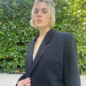 May include: A black blazer with a single button closure. The blazer has a classic, tailored fit and is made of a smooth, wrinkle-resistant fabric.