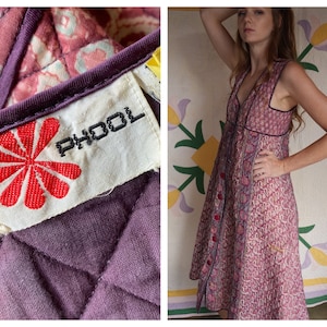 Puede incluir: Un vestido de algodón con estampado floral rosa y morado con cierre de botones en la parte delantera y una etiqueta que dice "PHOOL" con un logotipo de flor roja.