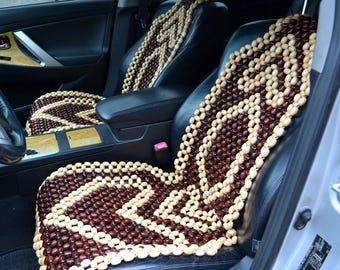 May include: A brown and beige wooden bead car seat cushion. The cushion is made of small, round beads that are woven together in a pattern. The cushion is placed in the driver's seat of a car.
