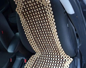 May include: A brown and beige wooden bead car seat cushion. The cushion is made of many small beads that are woven together to create a grid pattern.