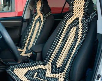 May include: Two wooden bead car seat covers in a black and beige pattern. The covers are made of small wooden beads that are strung together to create a grid pattern. The covers are in a car, and the driver's seat cover is partially visible.