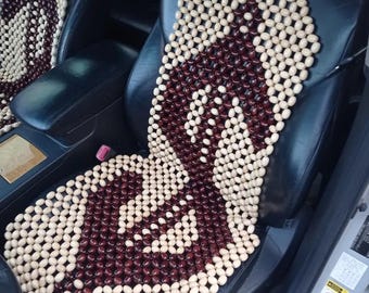 May include: A brown and beige wooden bead car seat cushion. The beads are arranged in a pattern that resembles a stylized letter 'S'.